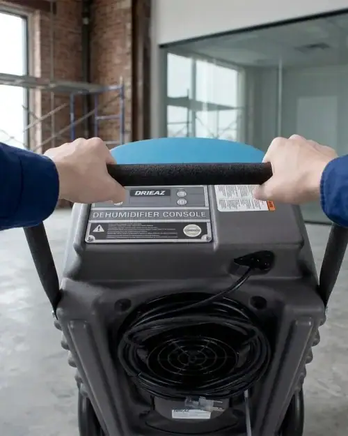 55L Industrial Dehumidifier Hire London | Dri-Eaz DrizAir 1200 (230V) 14 Industrial dehumidifier hire London – Hireload operative in hi-vis wheeling Drieaz unit in commercial warehouse