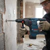 Cordless SDS Drill Hire London | Bosch 24V Rotary Hammer Drill (SDS Plus) 12 Worker with safety glasses drilling into wall using Bosch cordless SDS Plus rotary hammer on construction site