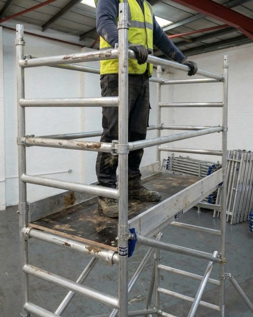 Industrial Scaffold Tower Hire (Single 0.85cm×1.8m) 10 Worker in hi-vis vest climbing onto a 1.8m scaffold tower platform with safety guardrails on site