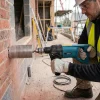 Dry Diamond Drill Hire London | Makita 8406 240V Diamond Core Drill 13 Dry diamond drill hire London operator core drilling through brick wall with Makita 8406 240V