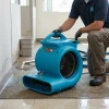 High Airflow Carpet Dryer Hire London | 2700 CFM 3 Speed Air Mover (240V) 15 High airflow carpet dryer hire being positioned by worker for property drying after water damage