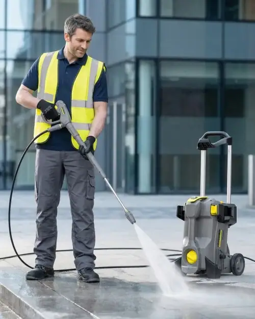 Professional in hi-vis vest using Kärcher HD 5/11 pressure washer hire to clean commercial paving in London