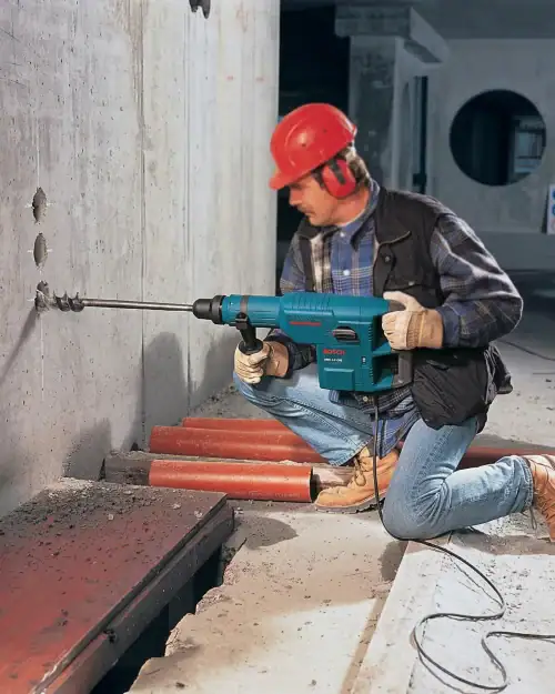 Rotary Hammer Hire London | Bosch GBH 11 DE SDS Max Combi Hammer (11kg) 18 Site operator in hard hat drilling horizontally through concrete with Bosch GBH 11 DE SDS Max combi hammer on demolition job