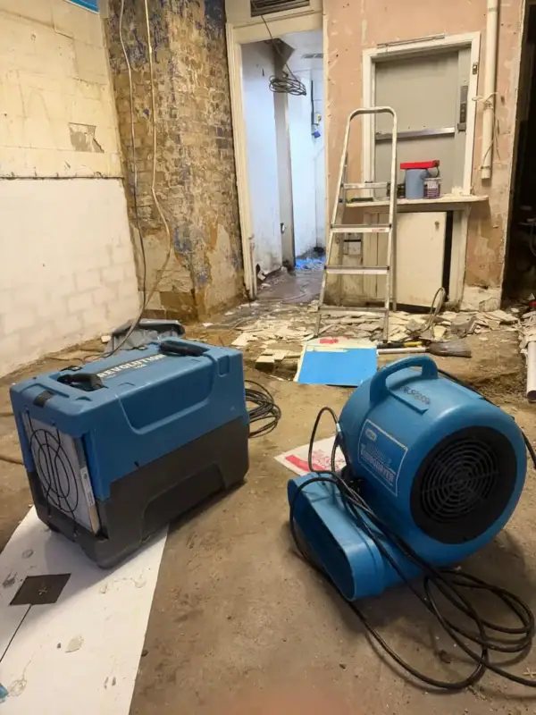 Industrial dehumidifier and air mover drying a water-damaged room in London